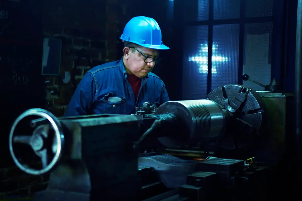 Technician in a blue hard hat working on an industrial machine
